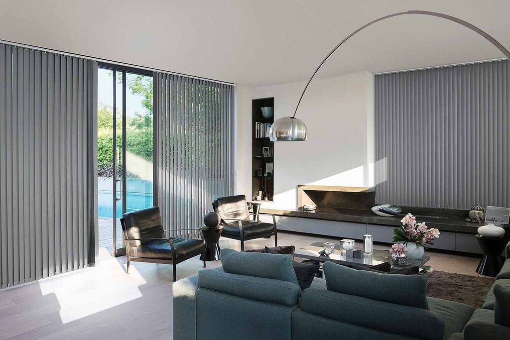 Grey vertical blinds tilted open along a glass wall and open patio door onto a pool