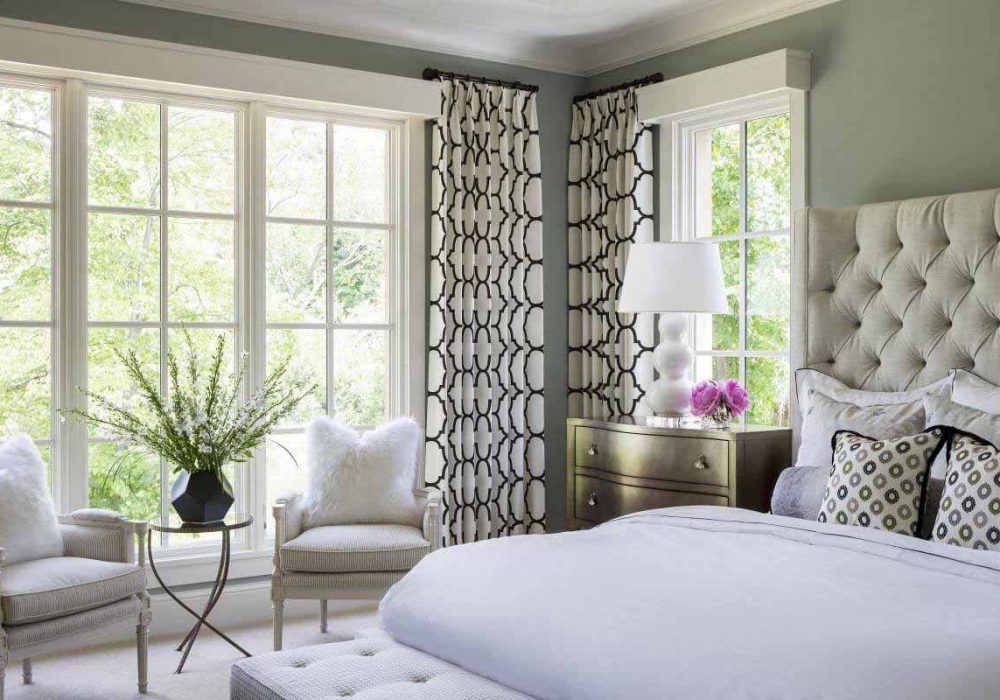 Black and white trellis-print curtains on a black rod in a sage bedroom with a tufted cream headboard