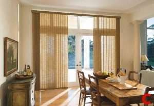 Tan textured vertical blinds across French doors and sidelights in a dining room with a wooden table