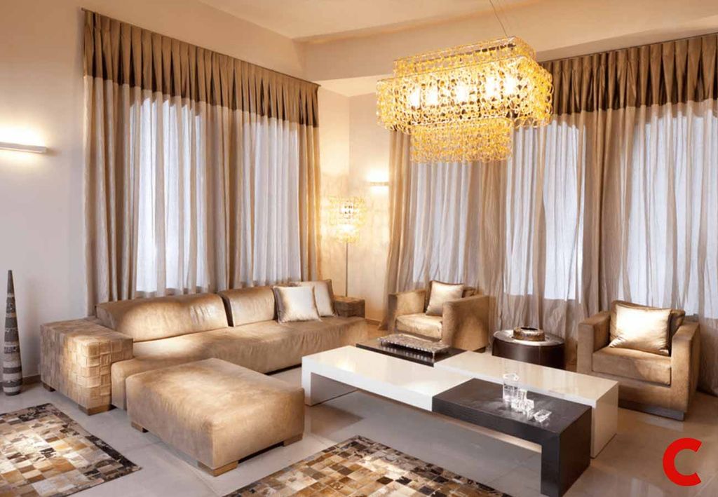 Beige pleated curtains under a matching valance running the full wall, white sheers behind, tan leather sofas
