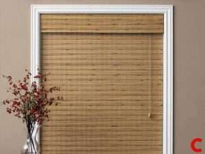 Honey bamboo roman blind lowered in a white-framed recess, with red berries in a vase beside it