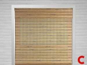Woven bamboo shade fully lowered in a white-framed window set into a white painted brick wall