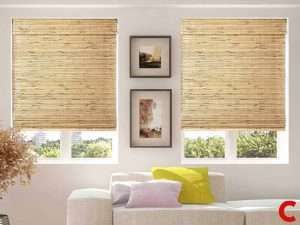 Two woven bamboo roman shades lowered over paired windows above a white sofa with lime and lilac cushions