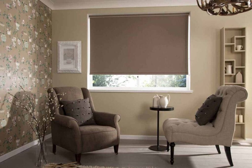 A mocha brown roller blind three-quarters lowered on a wide sitting-room window