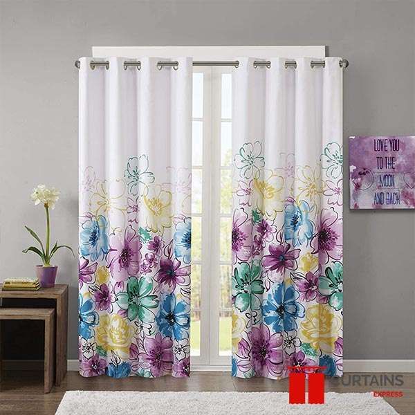 White eyelet curtains printed with a rising border of watercolour flowers, hung either side of a glazed door
