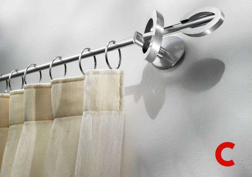 Brushed steel curtain pole with an open oval finial and rings, carrying a cream pleated sheer on a white wall