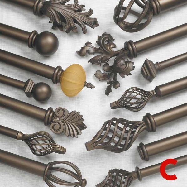 Flat-lay of bronze pole ends with assorted finials: balls, birdcage spirals, leaf scrolls and an amber glass knob