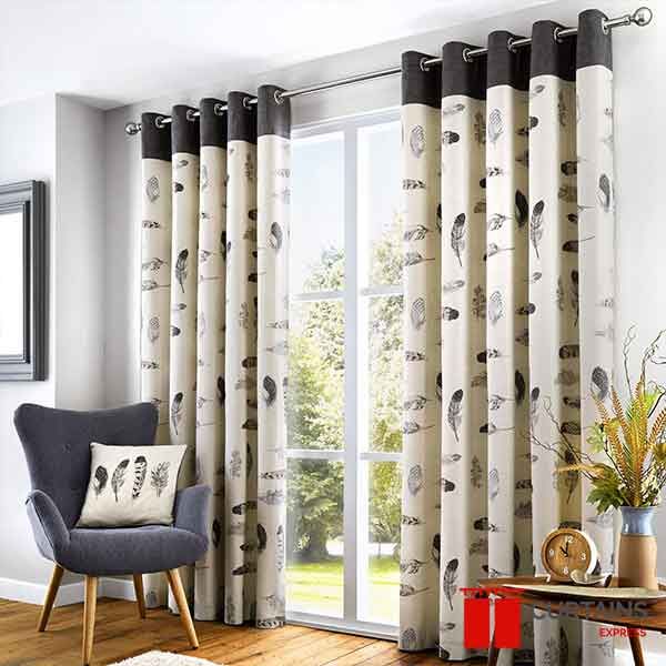 Cream feather-print eyelet curtains with a charcoal top band, open either side of doors onto a garden