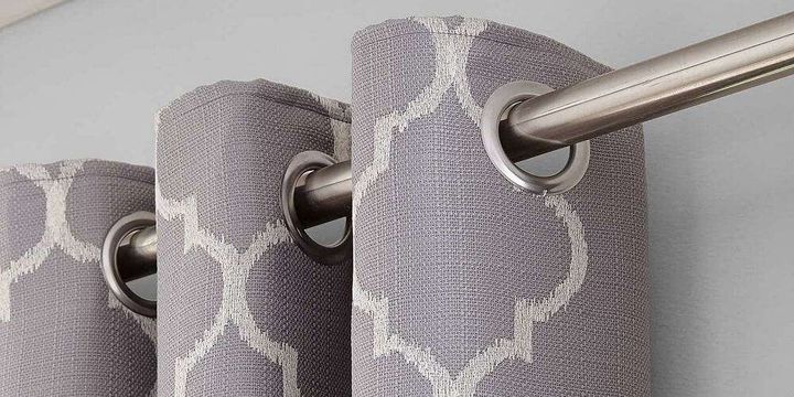 Close view of metal eyelets threaded onto a curtain pole above an embroidered weave
