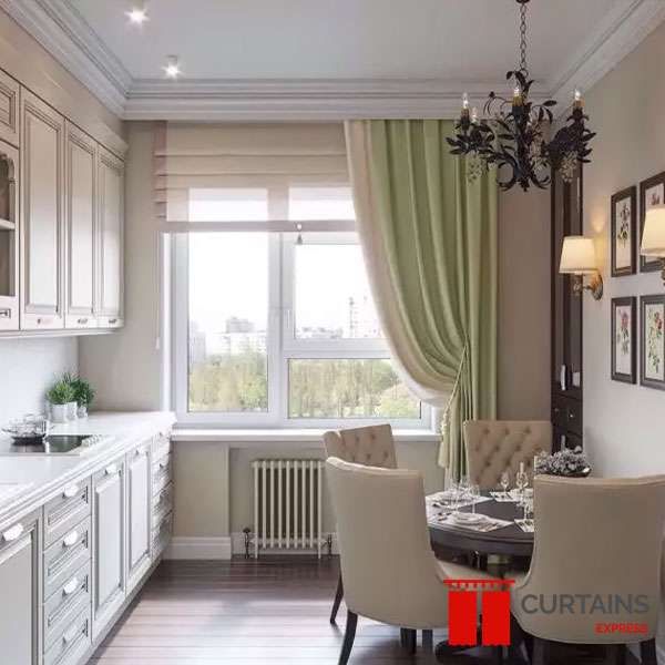 Sage green curtain swept to one side beside a cream roman blind at a kitchen-diner window, radiator below