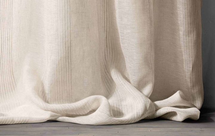 Close view of a slubbed linen curtain hem breaking against a dark floor