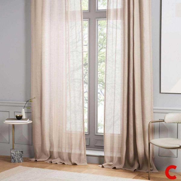 Blush sheer linen curtains falling to the floor at a tall panelled window, tree branches visible through the fabric