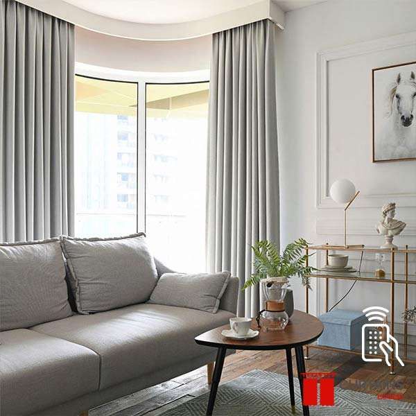 Pale grey curtains on a curved ceiling track wrapping a bowed corner window in a high-rise living room