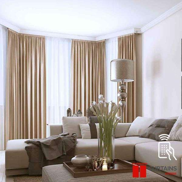 Camel satin curtains layered over white sheers around a corner window behind a beige sectional sofa