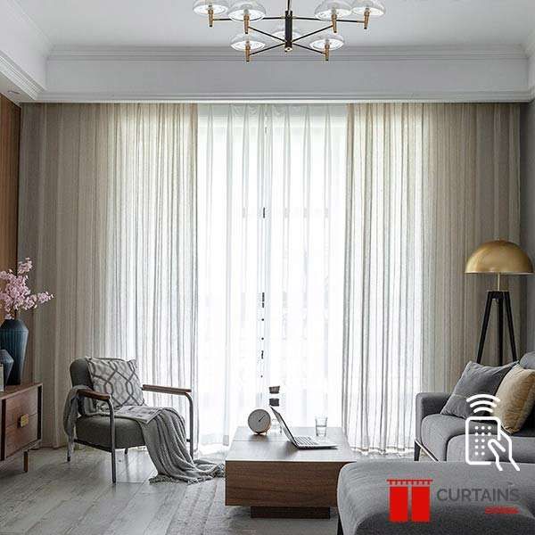 Greige curtains parted over a white sheer at a floor-to-ceiling balcony window in a grey-toned living room