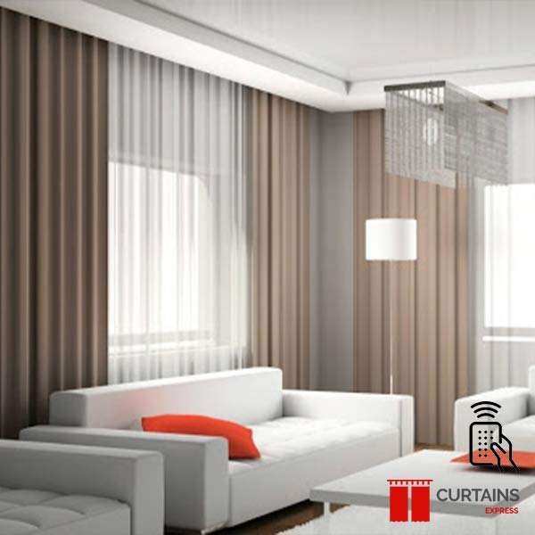 Taupe curtains layered over white sheers along a window wall, below a square crystal pendant light