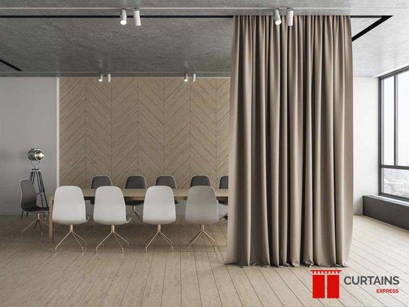 A full-height beige curtain on a ceiling track dividing a loft meeting room from the window side