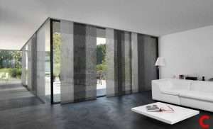 Grey sliding panel blinds drawn across a floor-to-ceiling glass wall in a white minimalist living room