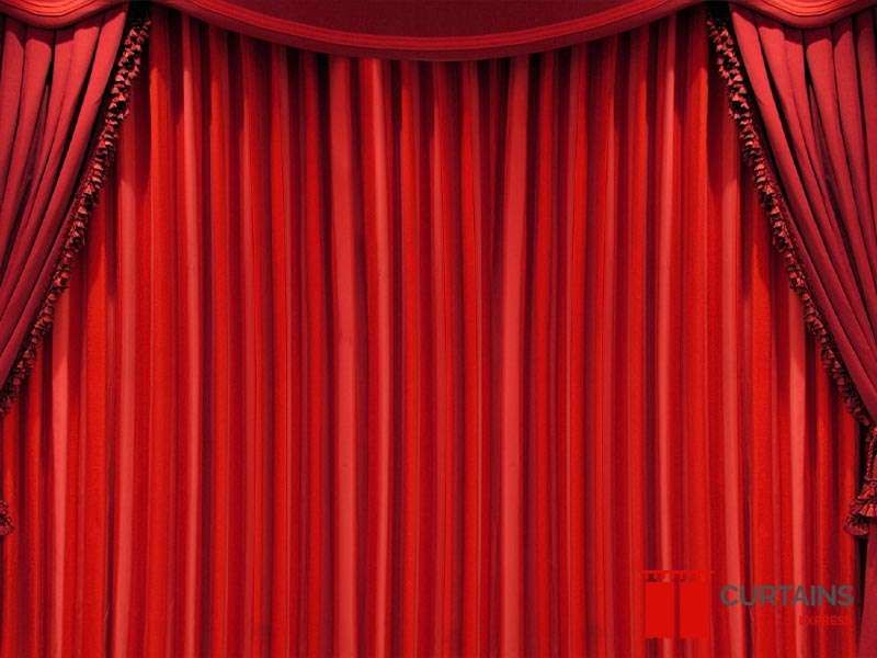 Red velvet theatre-style stage drapes with a swagged pelmet and tasselled tie-backs filling the frame