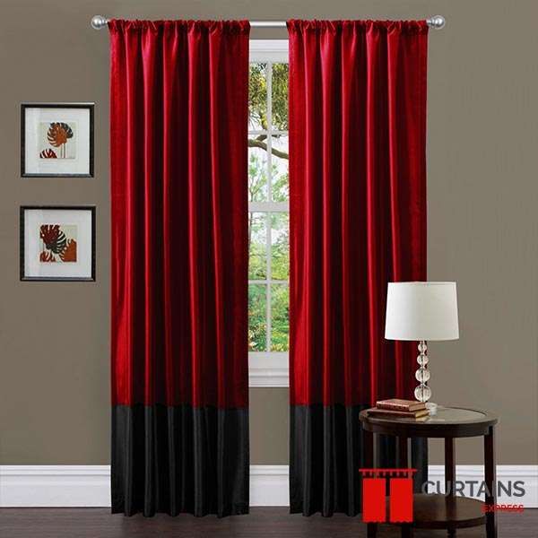 Red silk curtains with a deep black bottom band on a chrome pole either side of a white sash window