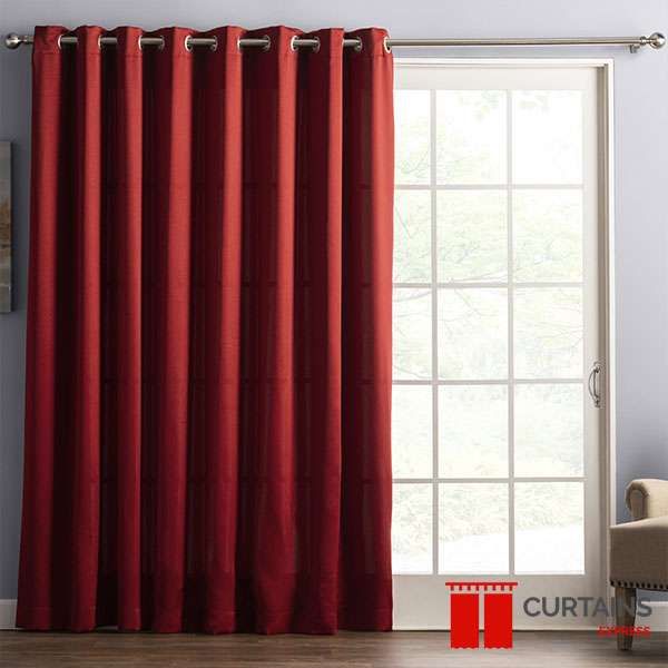 One wide burgundy eyelet panel pulled clear of a white-framed patio door in a grey room