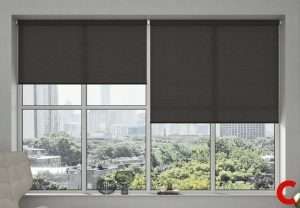 Two charcoal roller blinds lowered a third of the way down a wide window facing parkland and city towers
