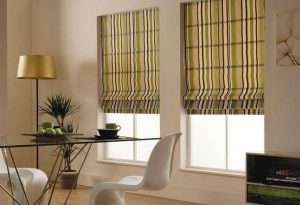 Olive and cream striped roman blinds half lowered over two windows in a glass-topped dining area