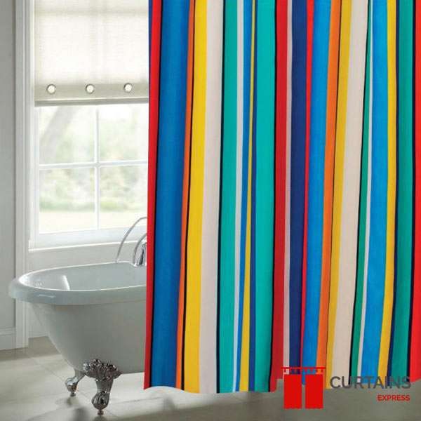 Brightly striped multicoloured shower curtain hanging beside a white clawfoot bath, small roman blind at the window