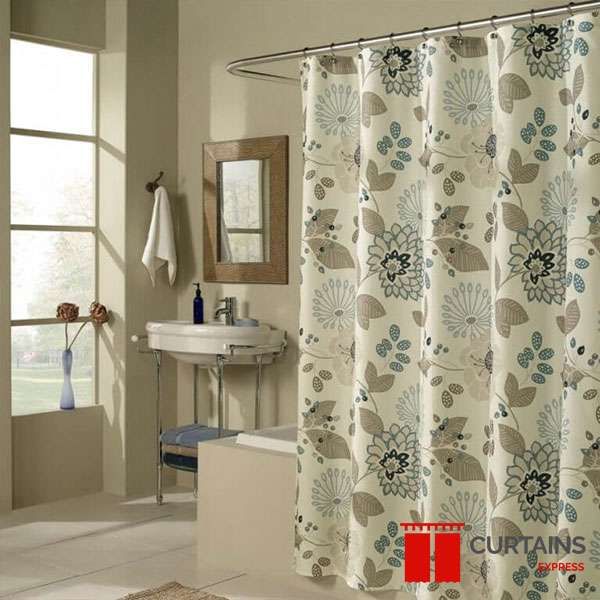 Cream shower curtain printed with blue and taupe stylised flowers, hung on a curved rail by a pedestal basin