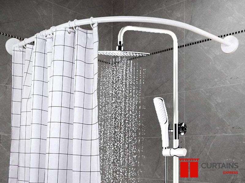 White shower curtain with a thin black grid check on a curved corner rail, rainfall shower running behind