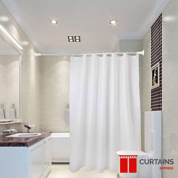 Plain white shower curtain drawn along a straight rail over a bath in a beige-tiled bathroom