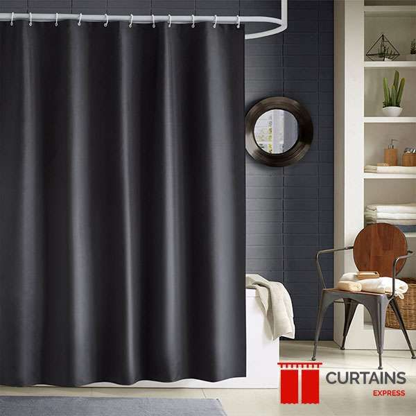 Plain black shower curtain on a white rail against a navy brick-tiled wall, with a round porthole mirror alongside