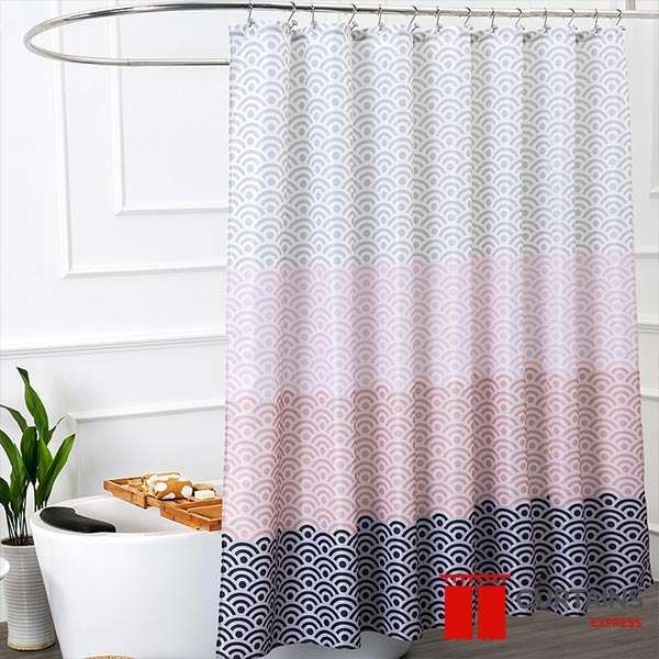 Shower curtain printed in grey, pink and navy scalloped waves on a curved rail beside a freestanding white tub