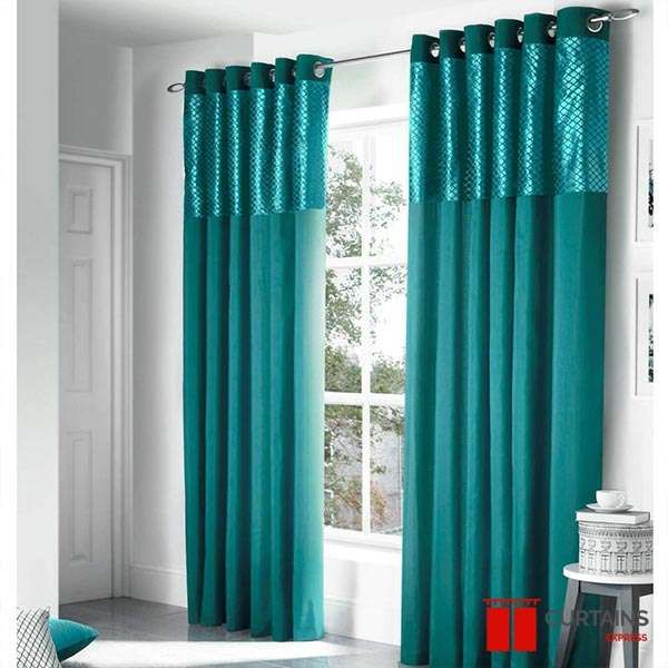 Teal eyelet curtains with a glossy lattice top band, hung on a slim rod at a white-framed corner window