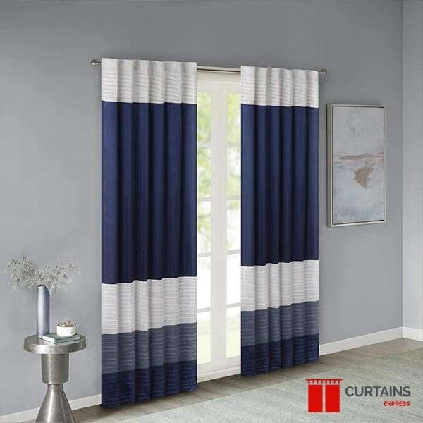 Navy, silver and white horizontally banded curtain panels on a rod at a glazed door in a grey room