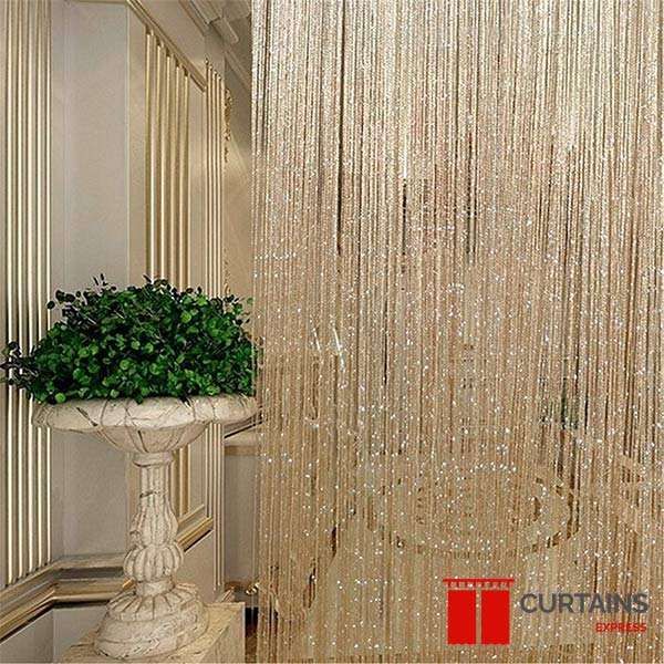 Champagne beaded string curtain hung as a divider next to a gilt-panelled wall and a stone urn planter