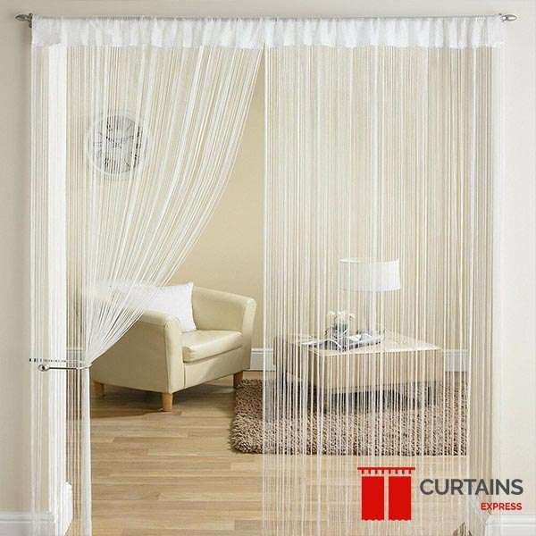 Ivory string curtains on a slim pole in a doorway, one panel tied back to show an armchair and lamp beyond