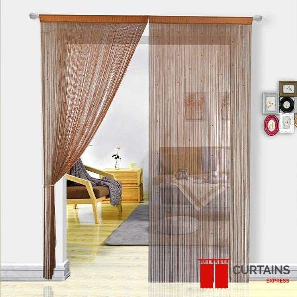 Brown beaded string curtains on a doorway pole, left panel tied back, opening onto a bedroom with a wooden chair