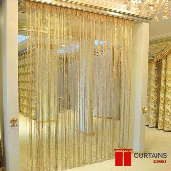 Gold string curtains filling a wide interior archway, with a chandelier above and patterned gold drapes to the right
