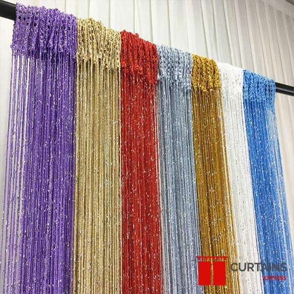 Seven string curtain panels in purple, beige, red, silver, gold, white and blue hung side by side on a black pole