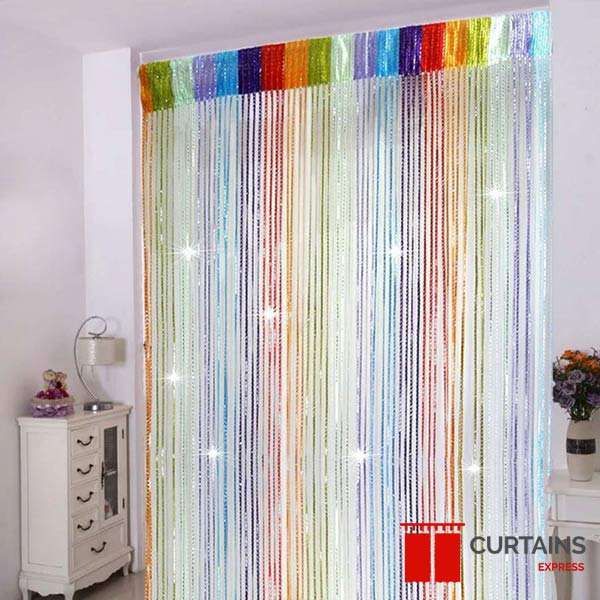 Rainbow-striped beaded string curtain hung in a doorway between a white chest of drawers and a vase of flowers