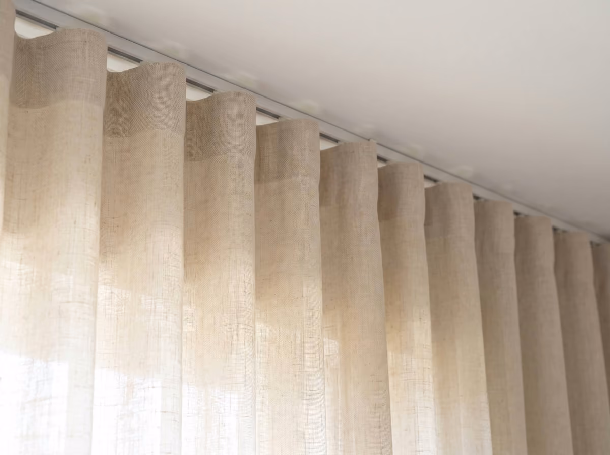 Off-white linen curtain in a wave heading, its top edge hung just below a white ceiling-fixed track