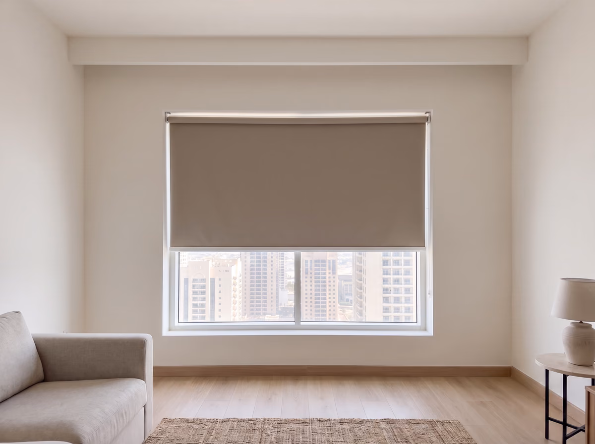 Taupe blackout roller blind lowered over the top half of a living room window, the towers clear in the glass below it